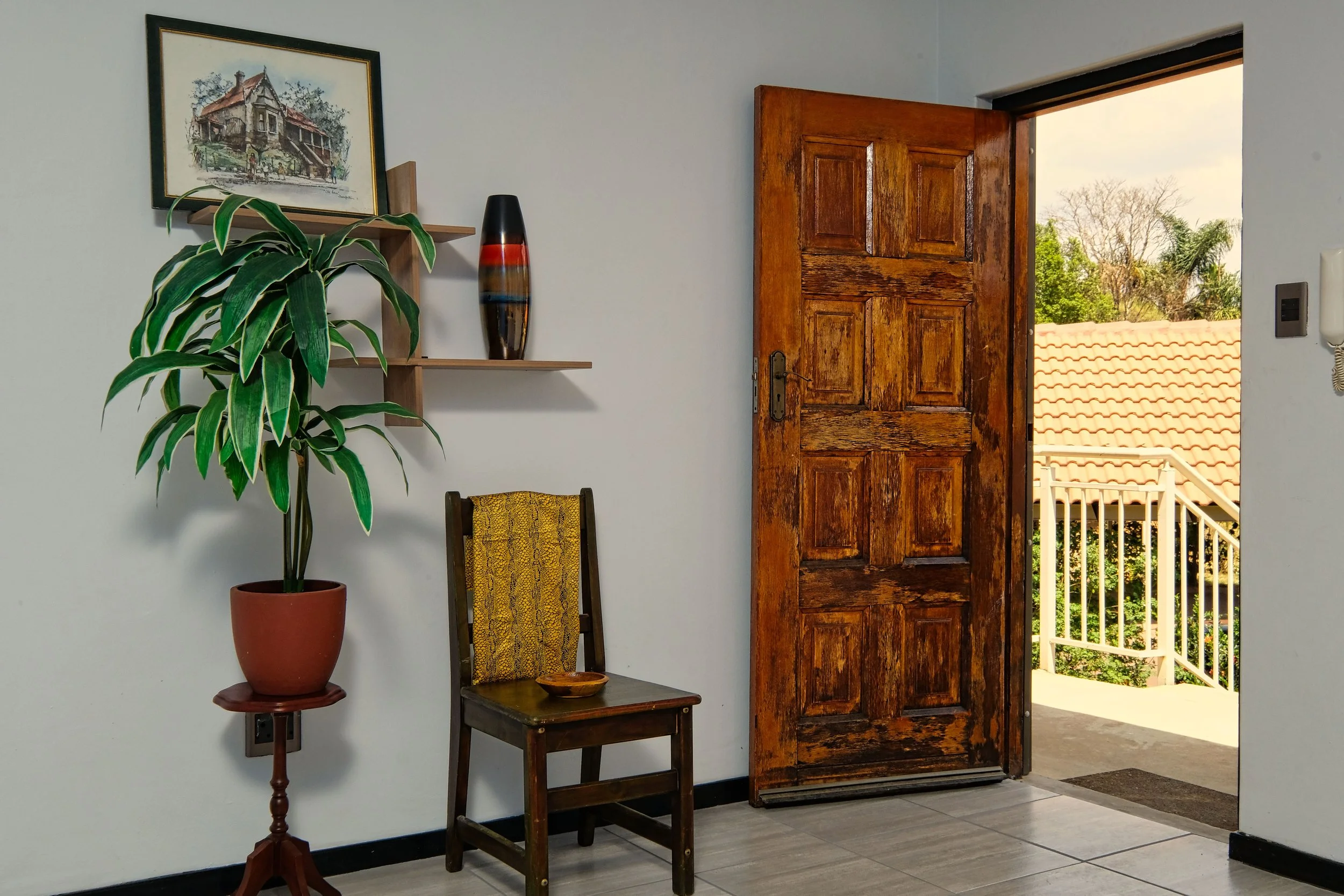 A Mexican hacienda with an open door showing sunlight outside, a chair and plant nearby, representing the threshold of possibility in family relationship repair therapy