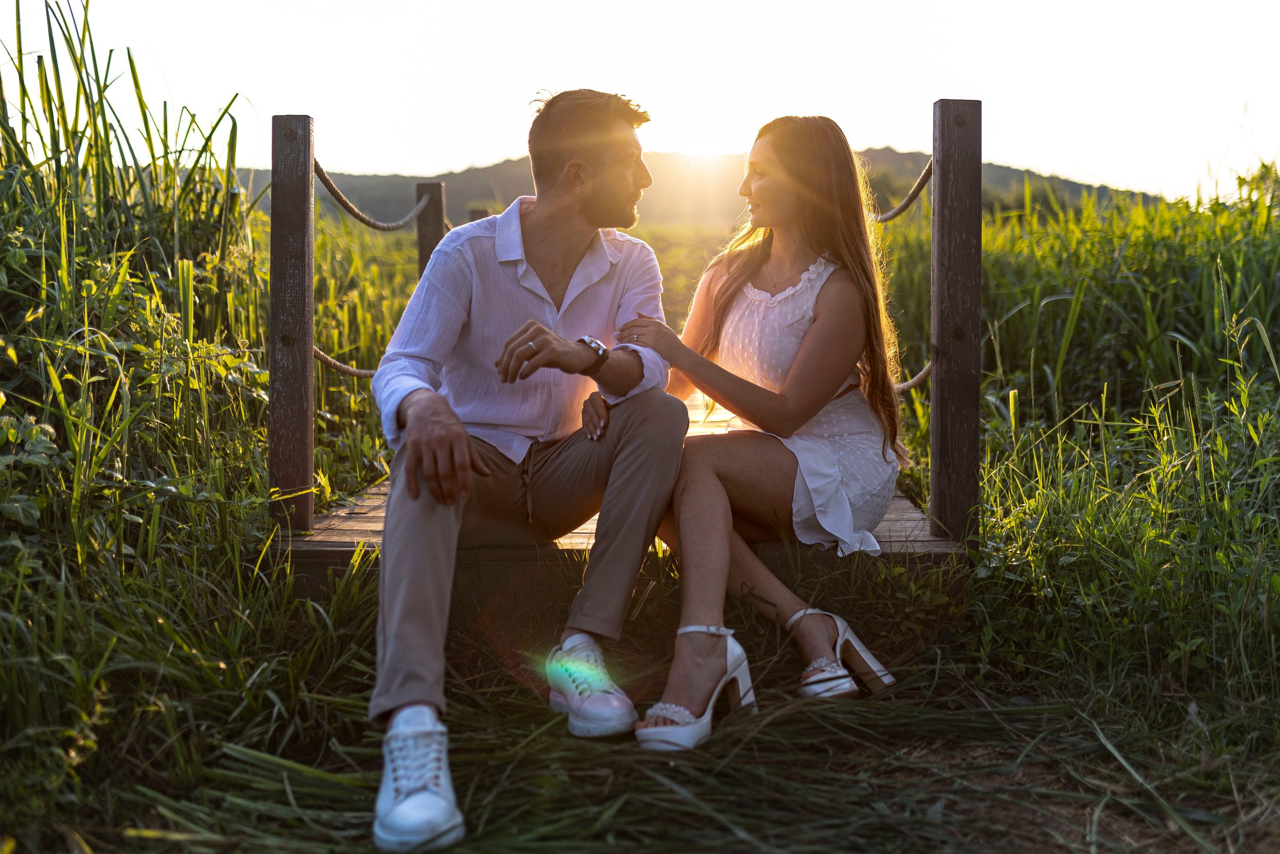 Couple sitting side by side on a dock watching the sunrise, symbolizing hope and relationship healing after betrayal.