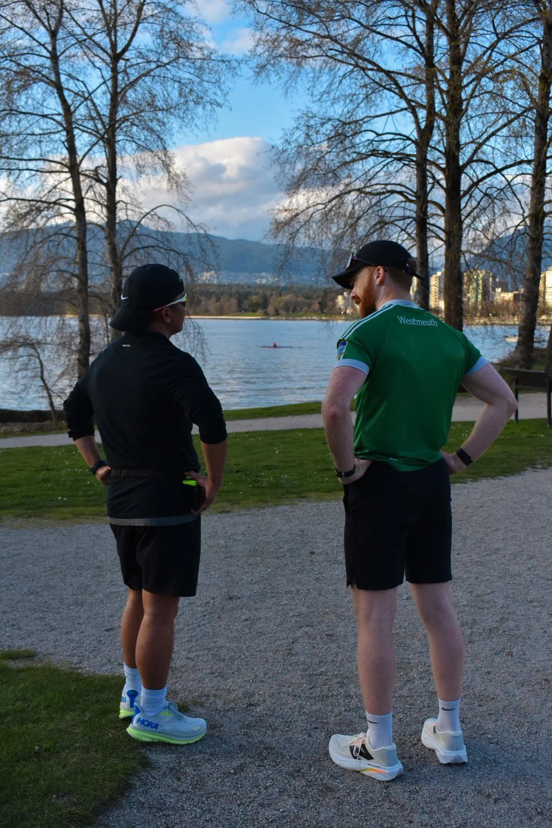 Two cyclists riding on a wet road during a race, wearing helmets and racing gear.