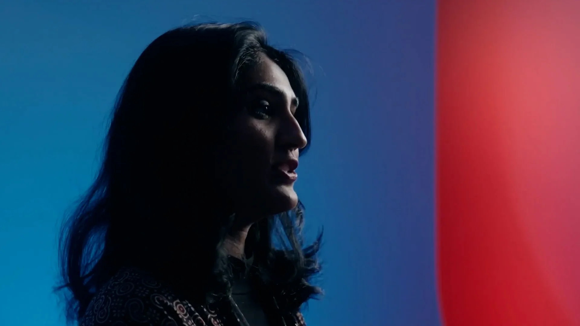 A woman with dark hair in profile silhouette against a colorful background with blue and red sections.