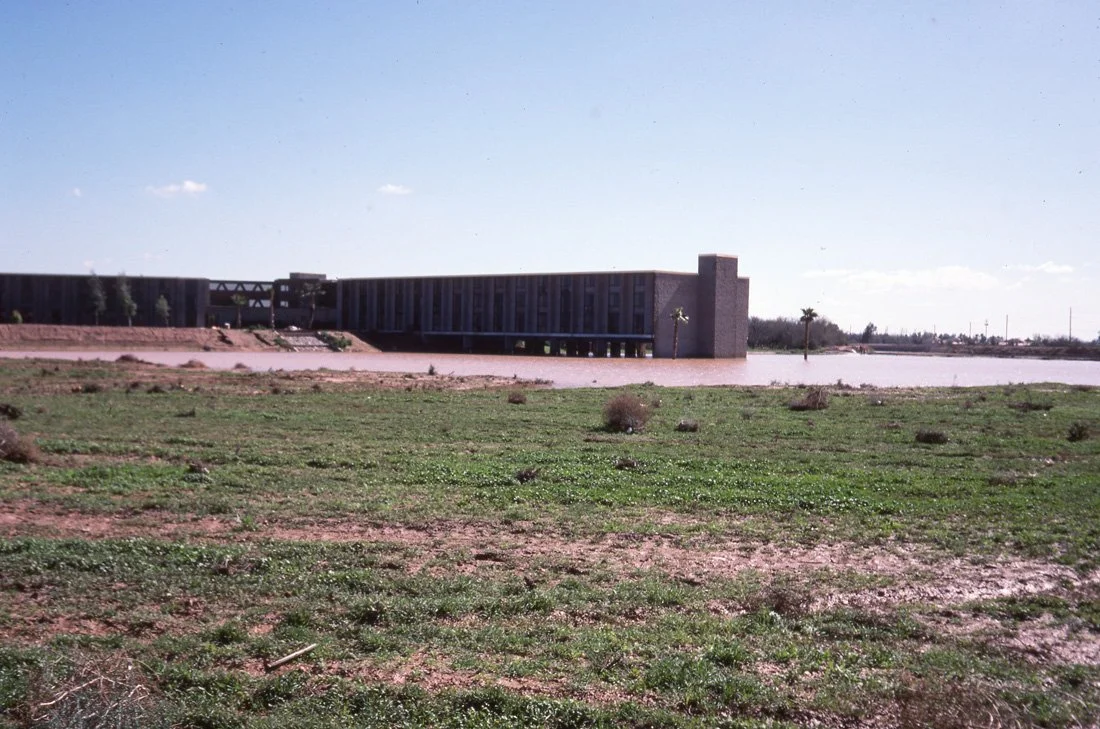 A dam with a water reservoir, metal gate, and concrete structure on a sunny day with blue sky.