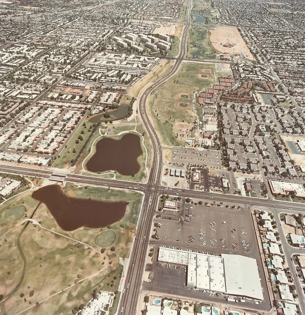 Aerial view of a city showing lakes, parks, roads, and residential and commercial buildings.