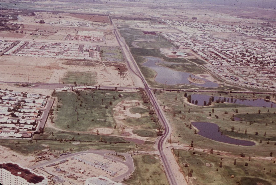 Aerial view of urban and suburban landscape with lakes, parks, and a highway running through.