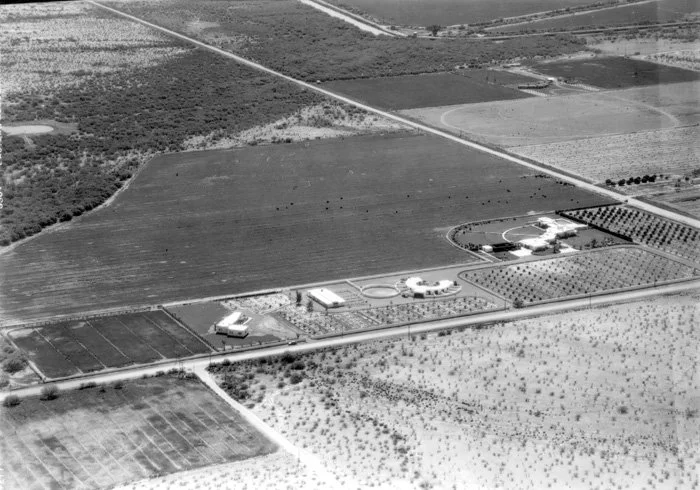 Aerial view of a farm with fields, farm buildings, and circular agricultural structures.