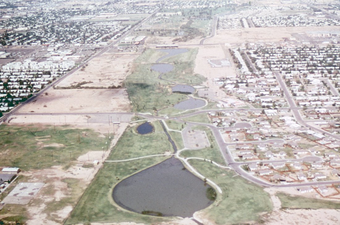 Aerial view of a city with a park featuring several small lakes and walking paths.
