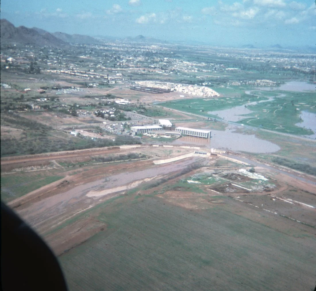 Aerial view of a landscape with mountains, farmland, and a river, taken from an airplane window.