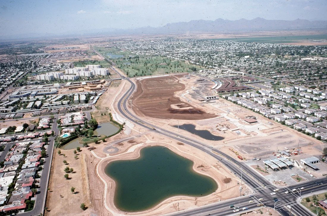 Aerial view of a developing urban area with construction sites, roads, lakes, and residential neighborhoods.