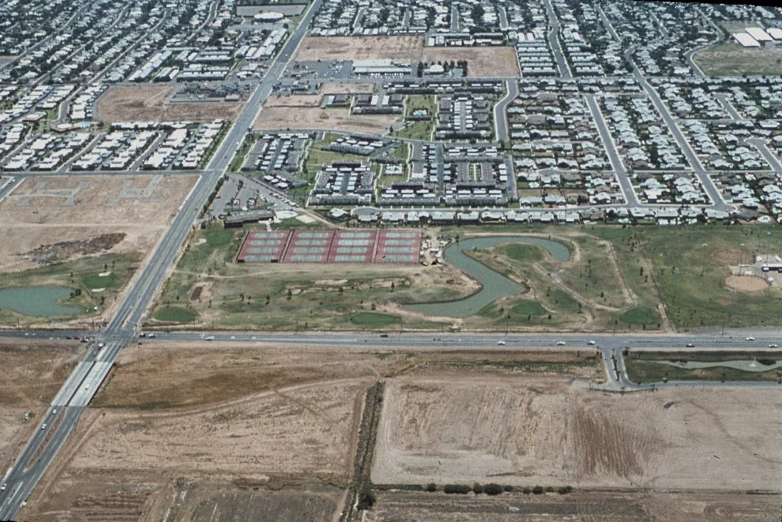 Aerial view of a suburban neighborhood with streets, houses, and a golf course with water hazards.