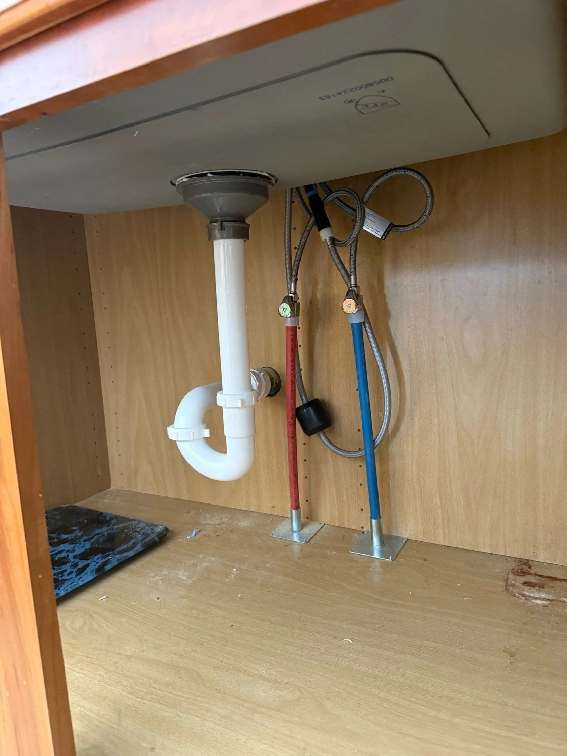Professional under-sink plumbing installation by RM Electric & Plumbing, featuring clean PEX supply lines and a properly fitted P-trap for a kitchen remodel.