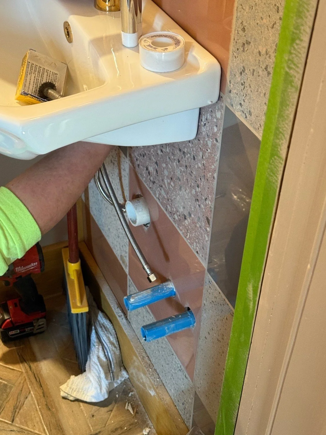 An RM Electric & Plumbing specialist performing a precision bathroom sink installation, featuring rough-in plumbing and high-end fixture setup.