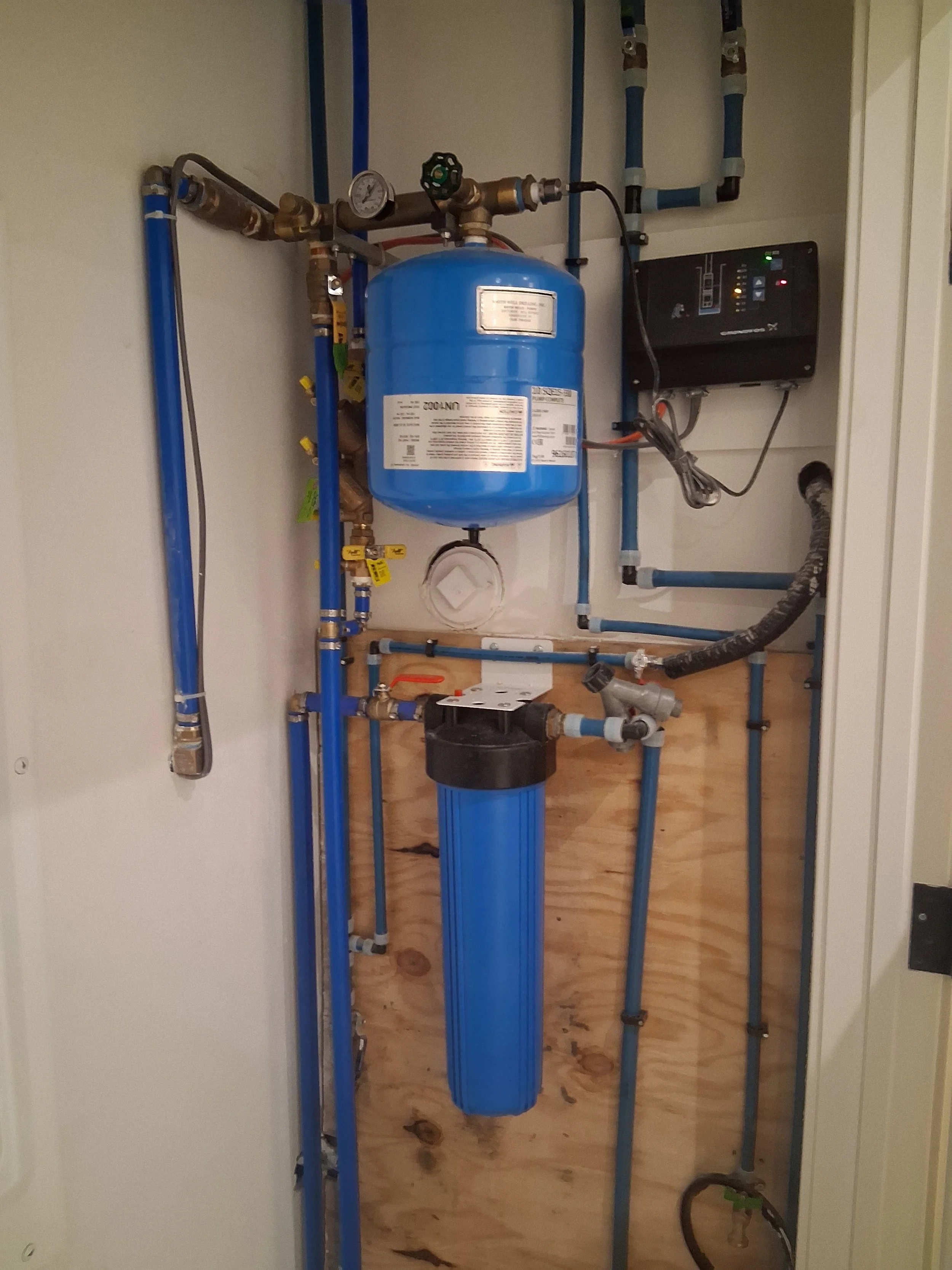 Professional installation of a residential well water system by RM Electric & Plumbing, featuring a thermal expansion tank, whole-house sediment filter, and digital pump controller.