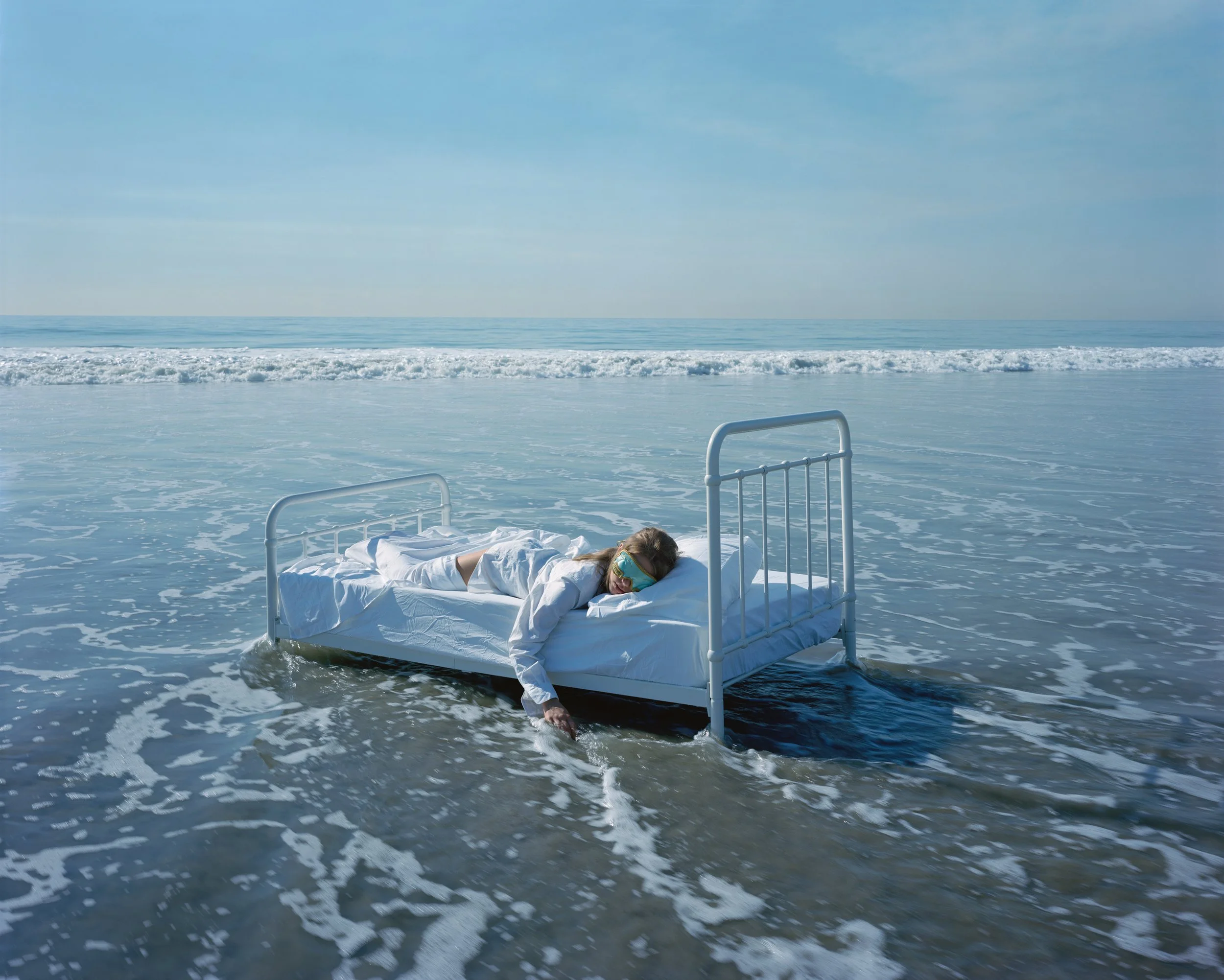 Breakfast at Tiffany’s by Tyler Shields, color photograph of a woman lying on a bed floating in the ocean, contemporary fine art photography