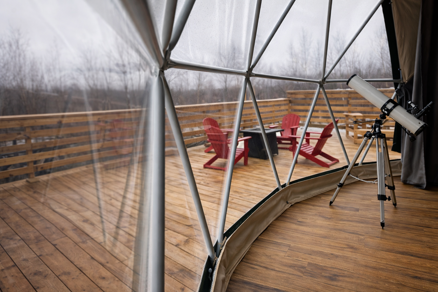 Telescope by window inside glamping dome for stargazing