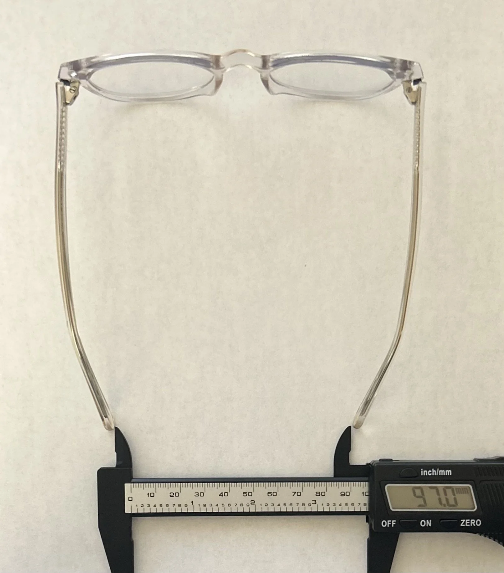 Digital caliper measuring a pair of glasses at 97.0 millimeters wide with Lil Fixer applied.