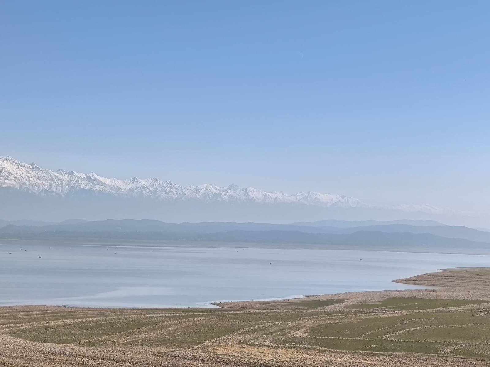 Snow-capped mountains and a lake under a clear blue sky