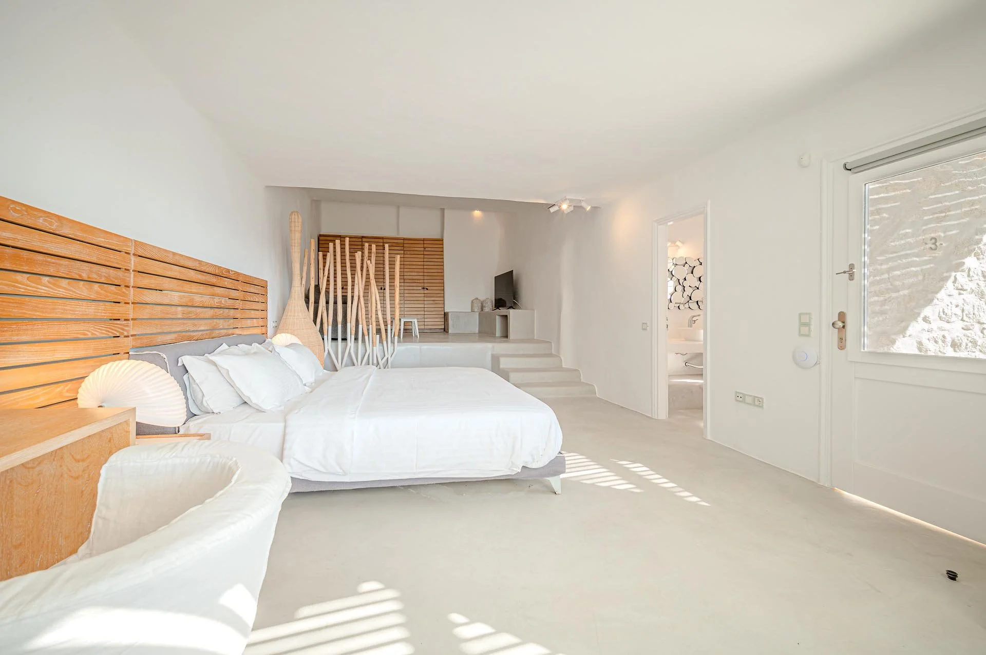 Hell erdgeschoss Schlafzimmer mit weißem Bett, Holz Kopfteil und natürlichen Beleuchtungselementen, Zugang zur Terrasse, moderne und minimalistische Inneneinrichtung.