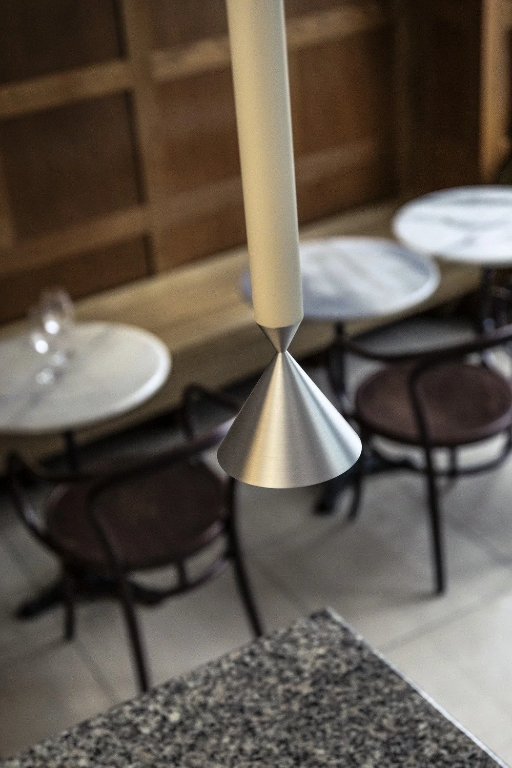 Close-up of a modern pendant light with a metallic cone shape, hanging over a kitchen or dining area.