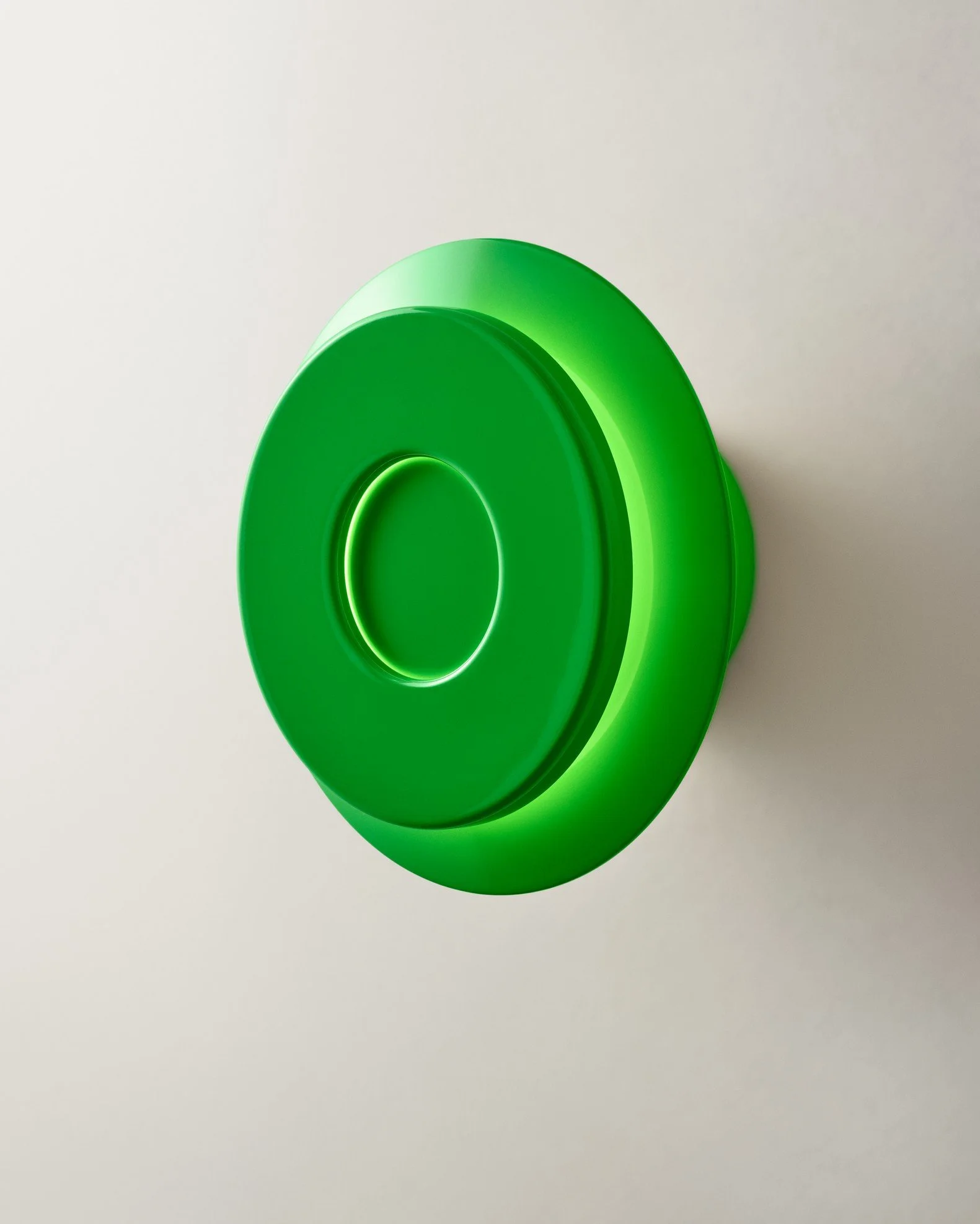 Green circular object with a hollow center mounted on a white wall.