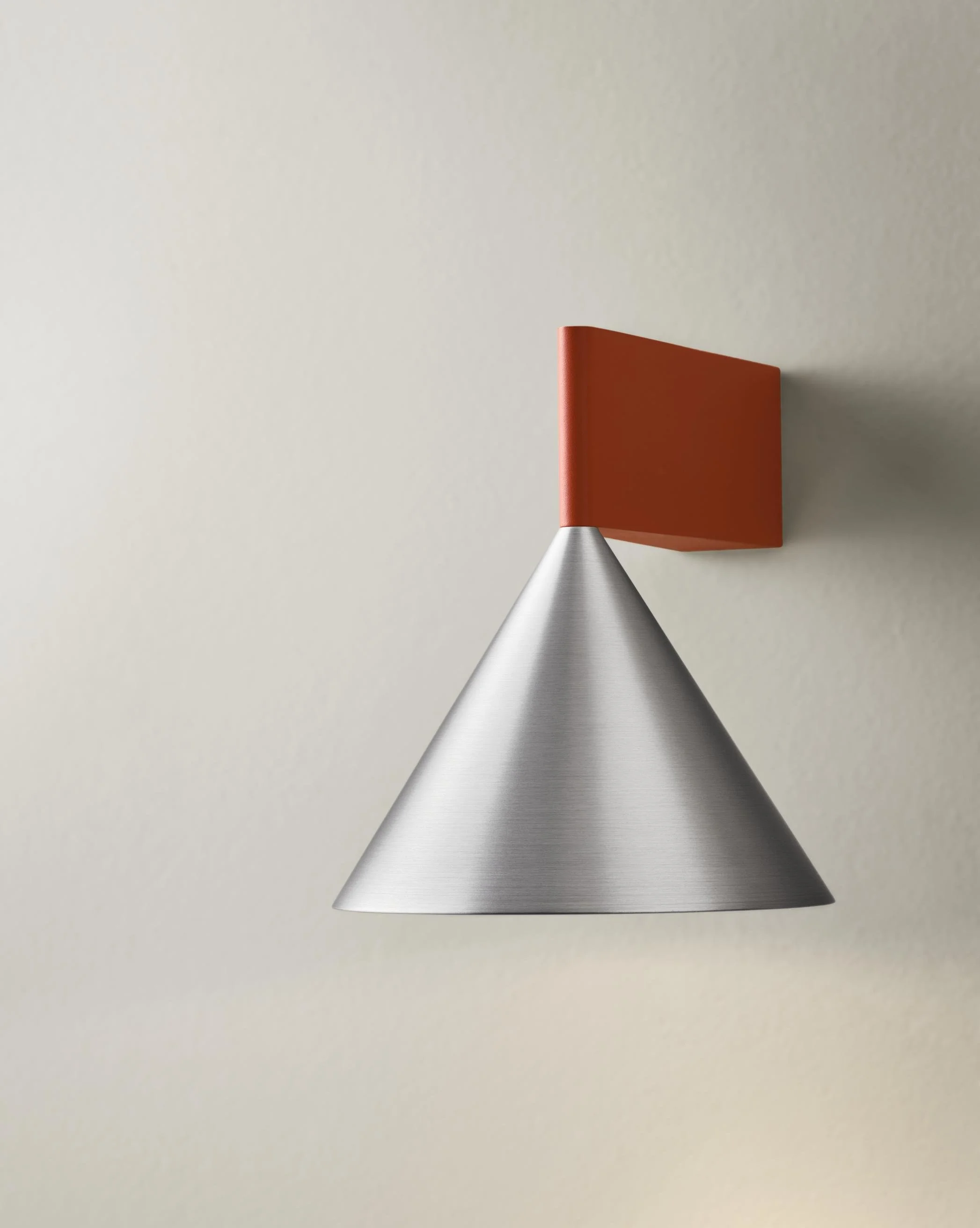 Modern wall sconce with a conical metallic shade and a rectangular orange backplate.