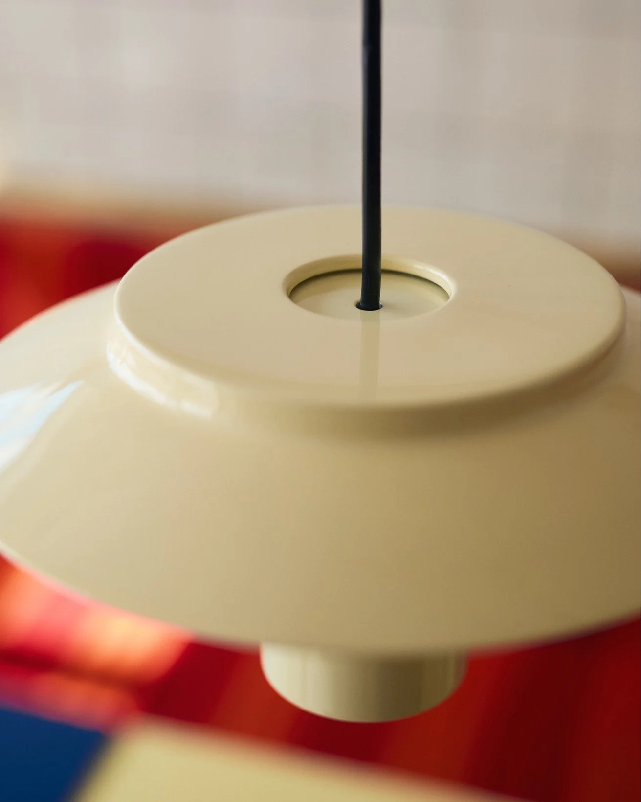Close-up of a beige lampshade with a black cord hanging through the top opening.