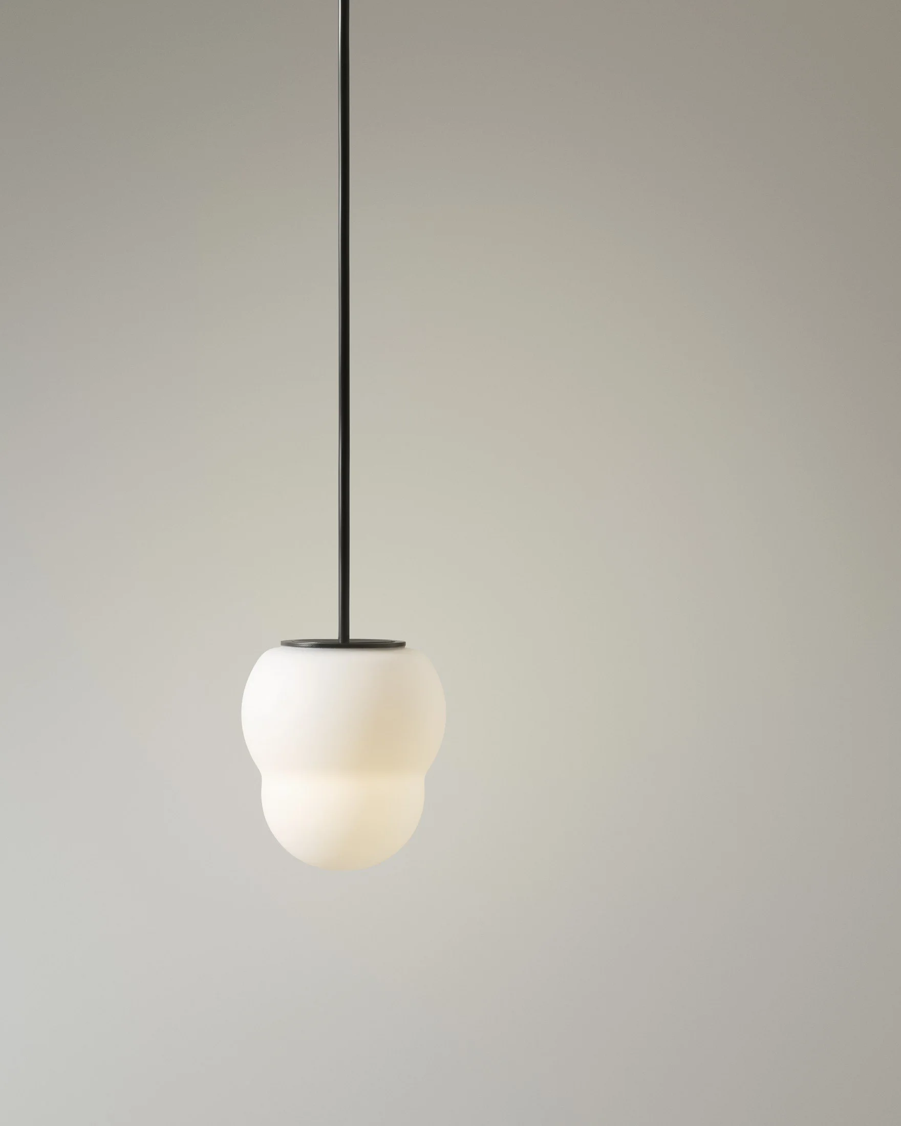 Modern pendant light with a frosted glass shade hanging from a black cord against a plain background.