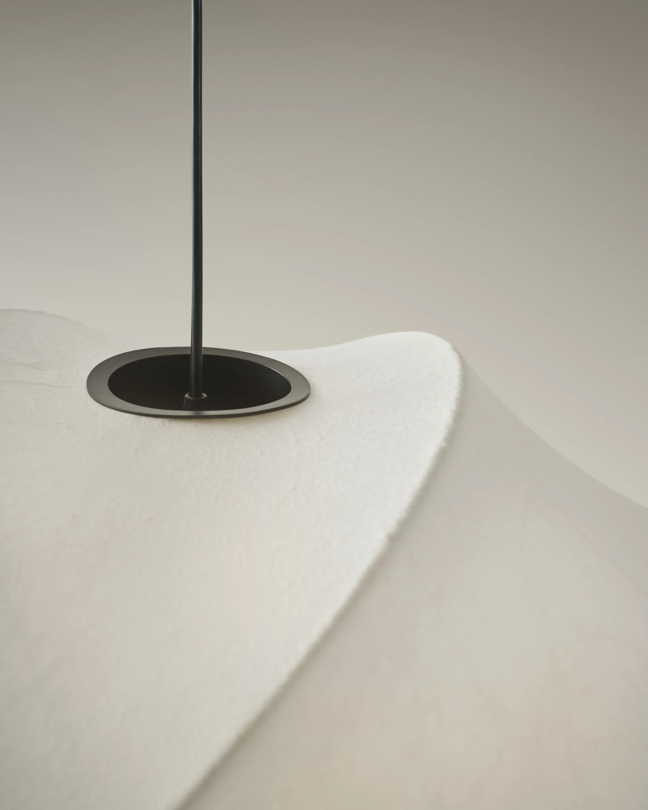 Close-up of a modern white textured surface with a black pole passing through a circular hole.