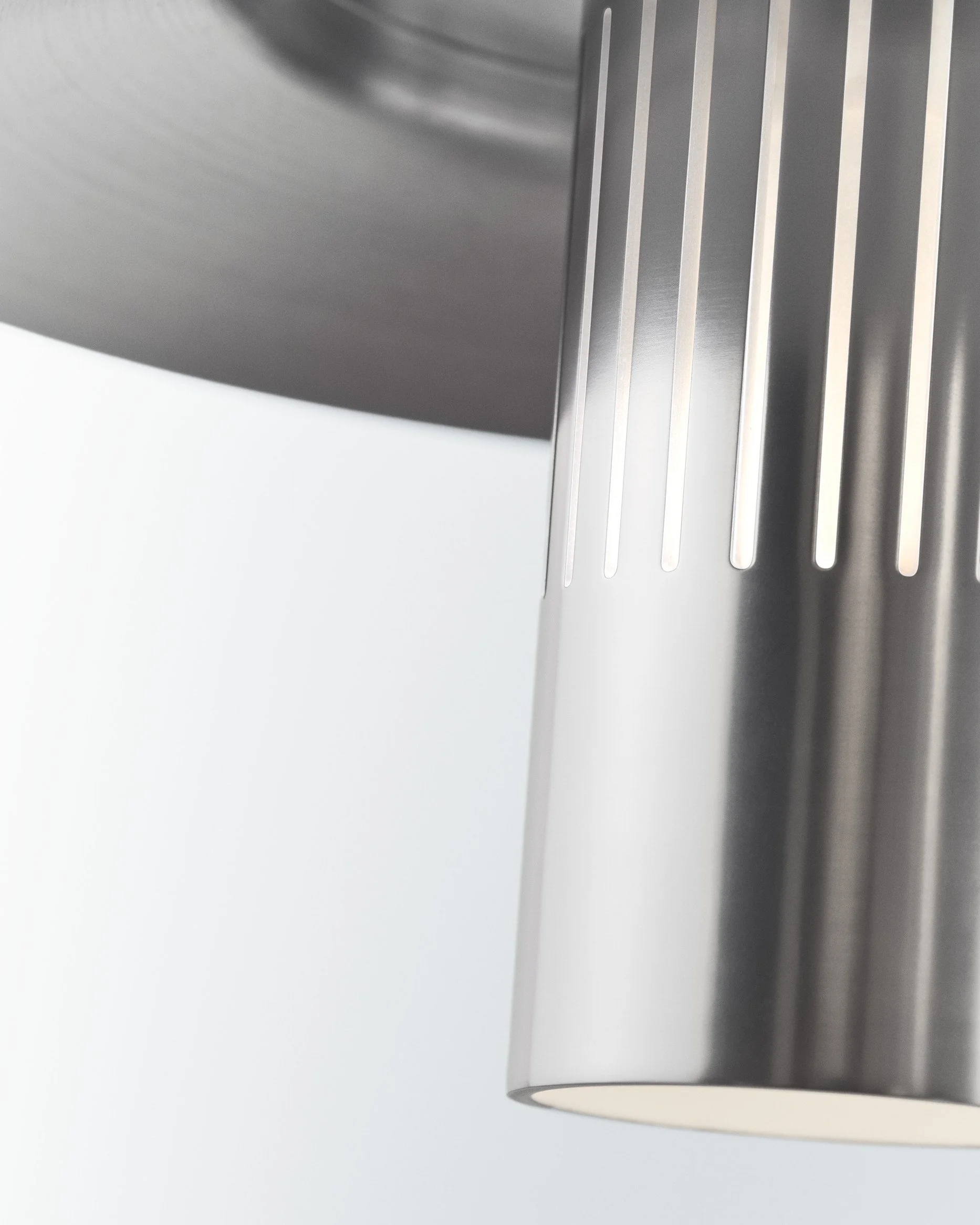 Close-up of a modern metallic ceiling light fixture with vertical slits.