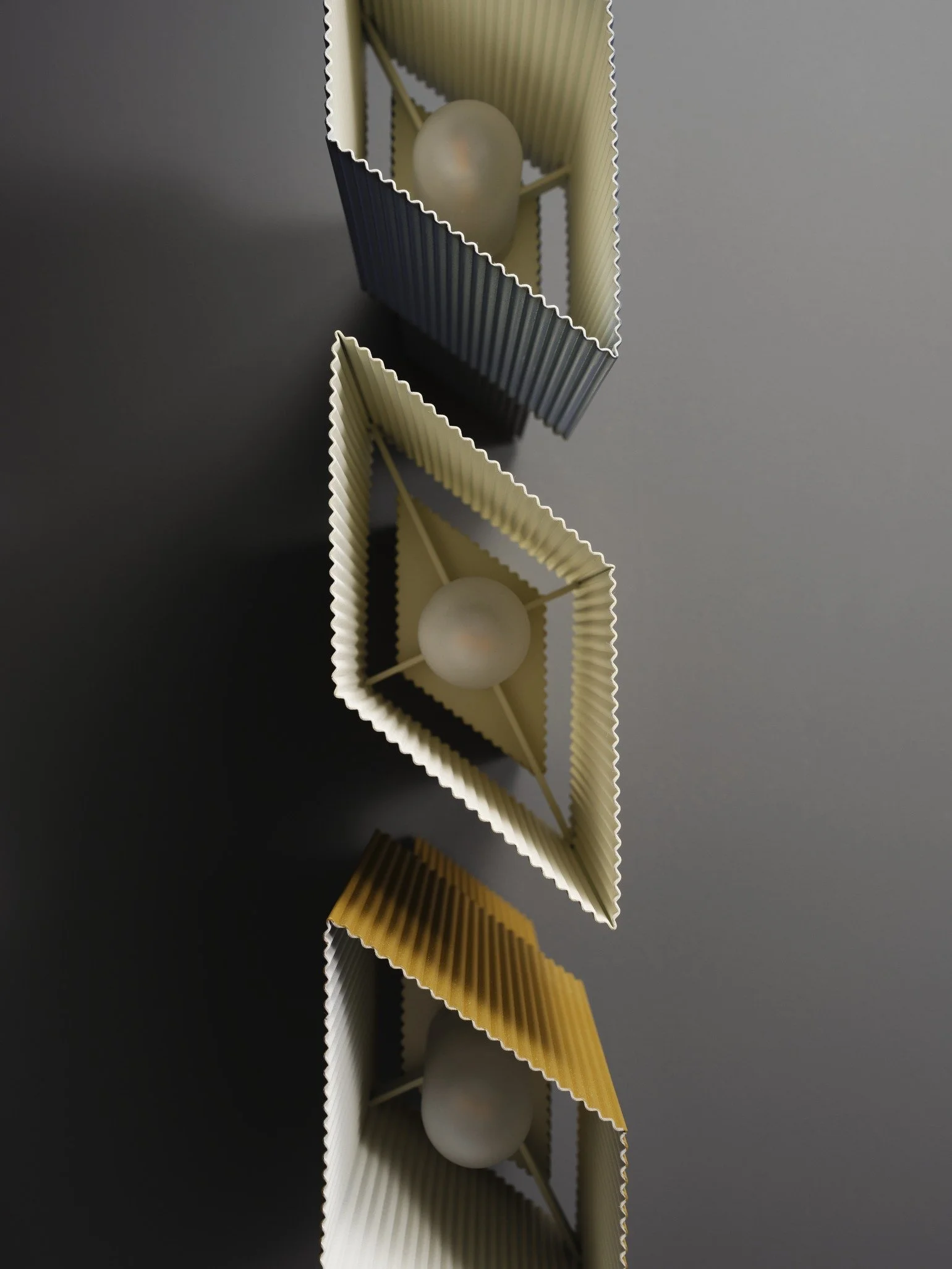 A reflection of vertically aligned colorful modern light fixtures with spherical bulbs, seen upside down on a dark surface.