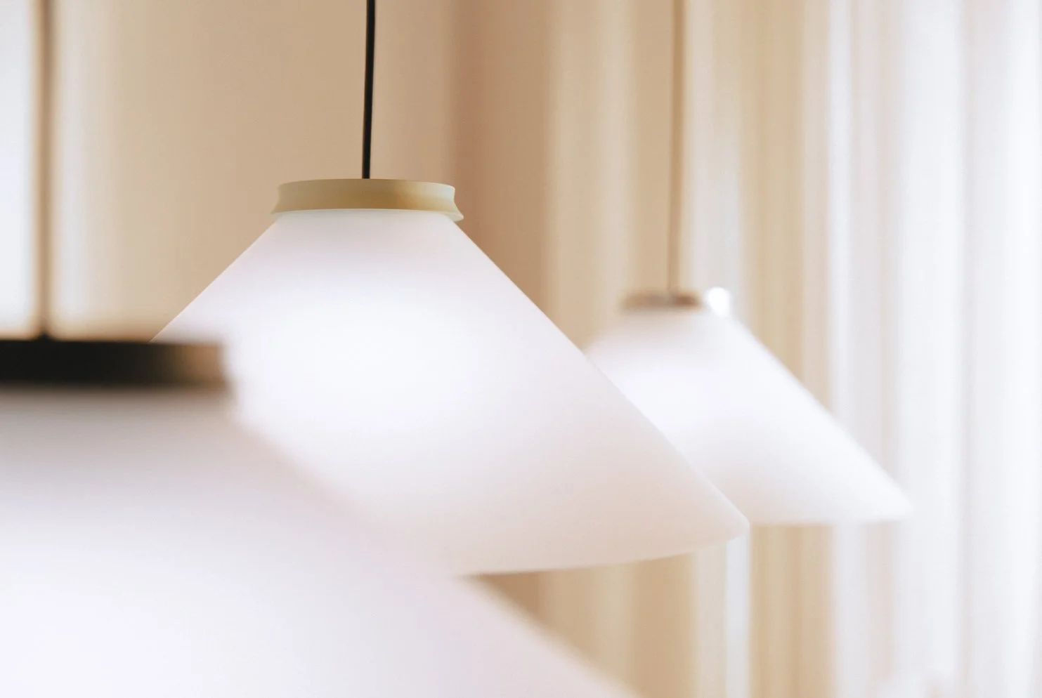 Close-up of a row of white conical pendant lamps hanging from the ceiling.
