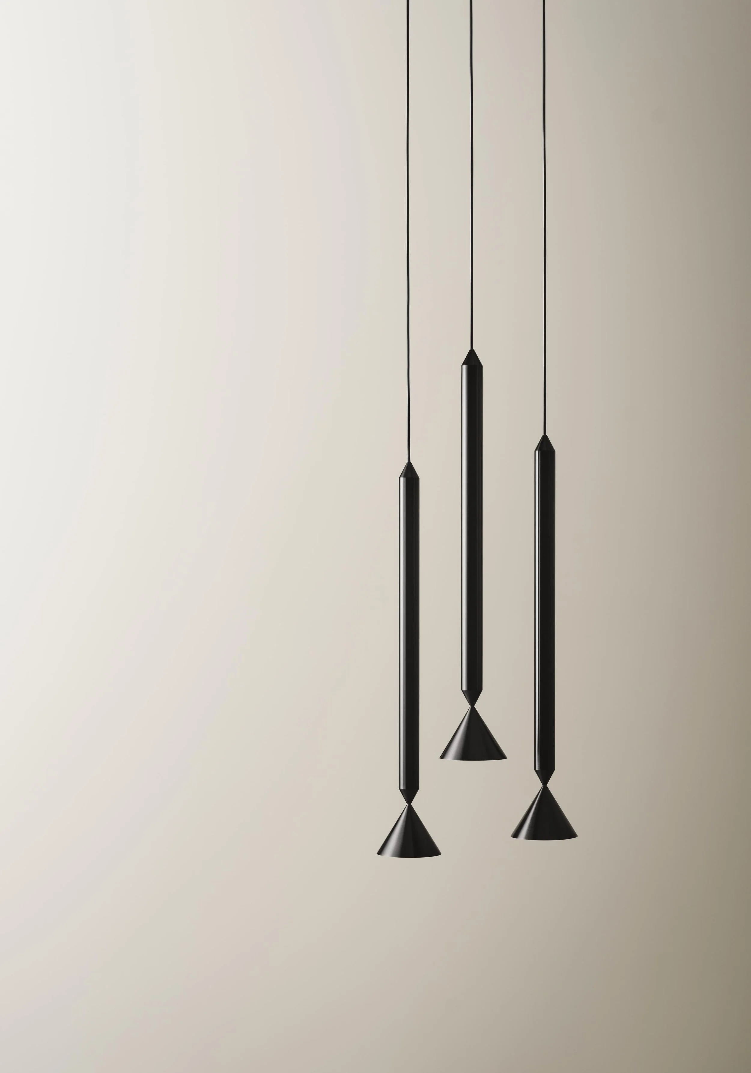 Modern black pendant lights hanging from cords against a neutral wall.
