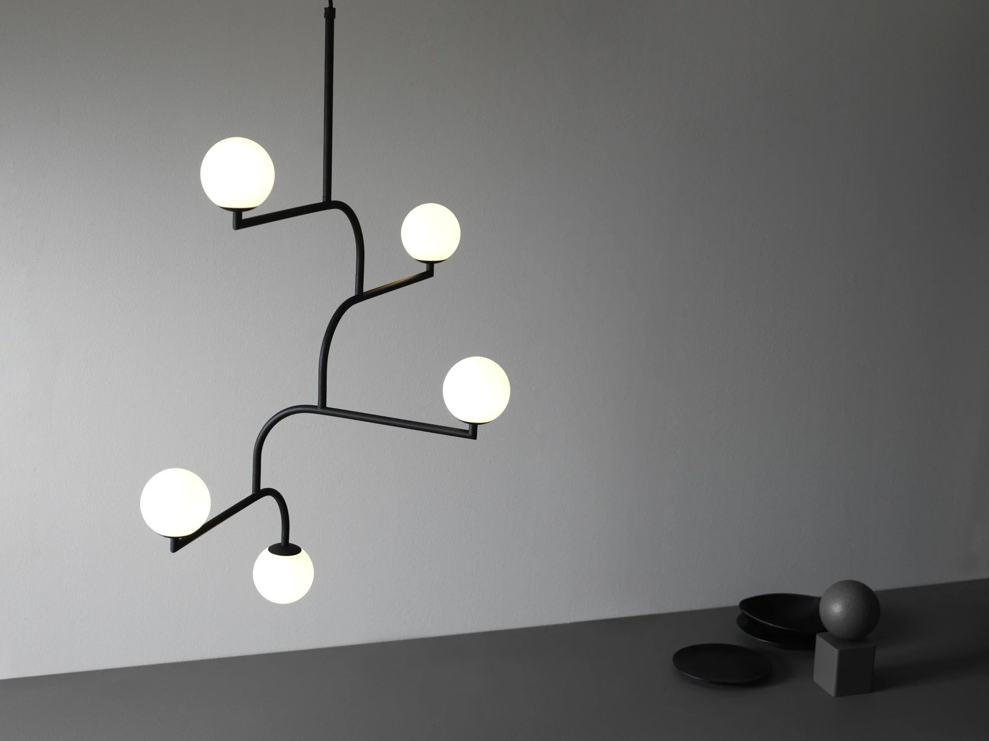 Modern pendant chandelier with six glowing spherical bulbs hanging from a black metal frame