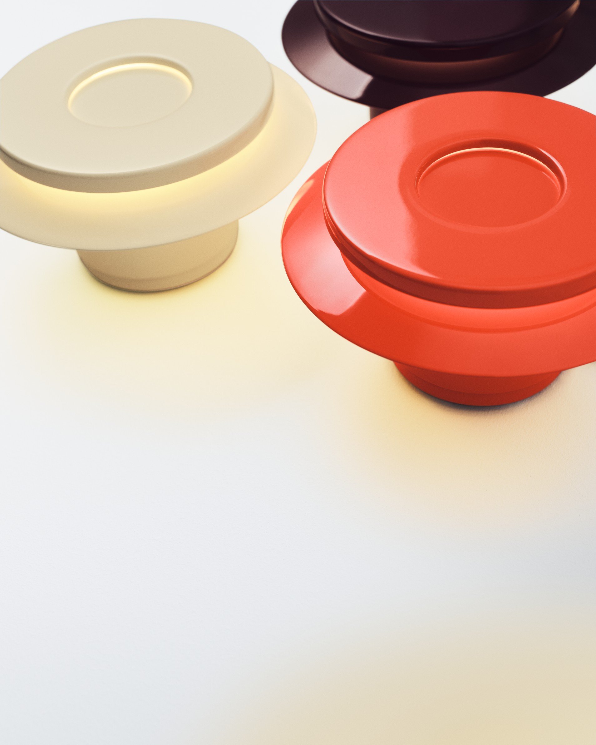 Three colorful wooden spinning tops in beige, red, and dark purple placed on a white surface.