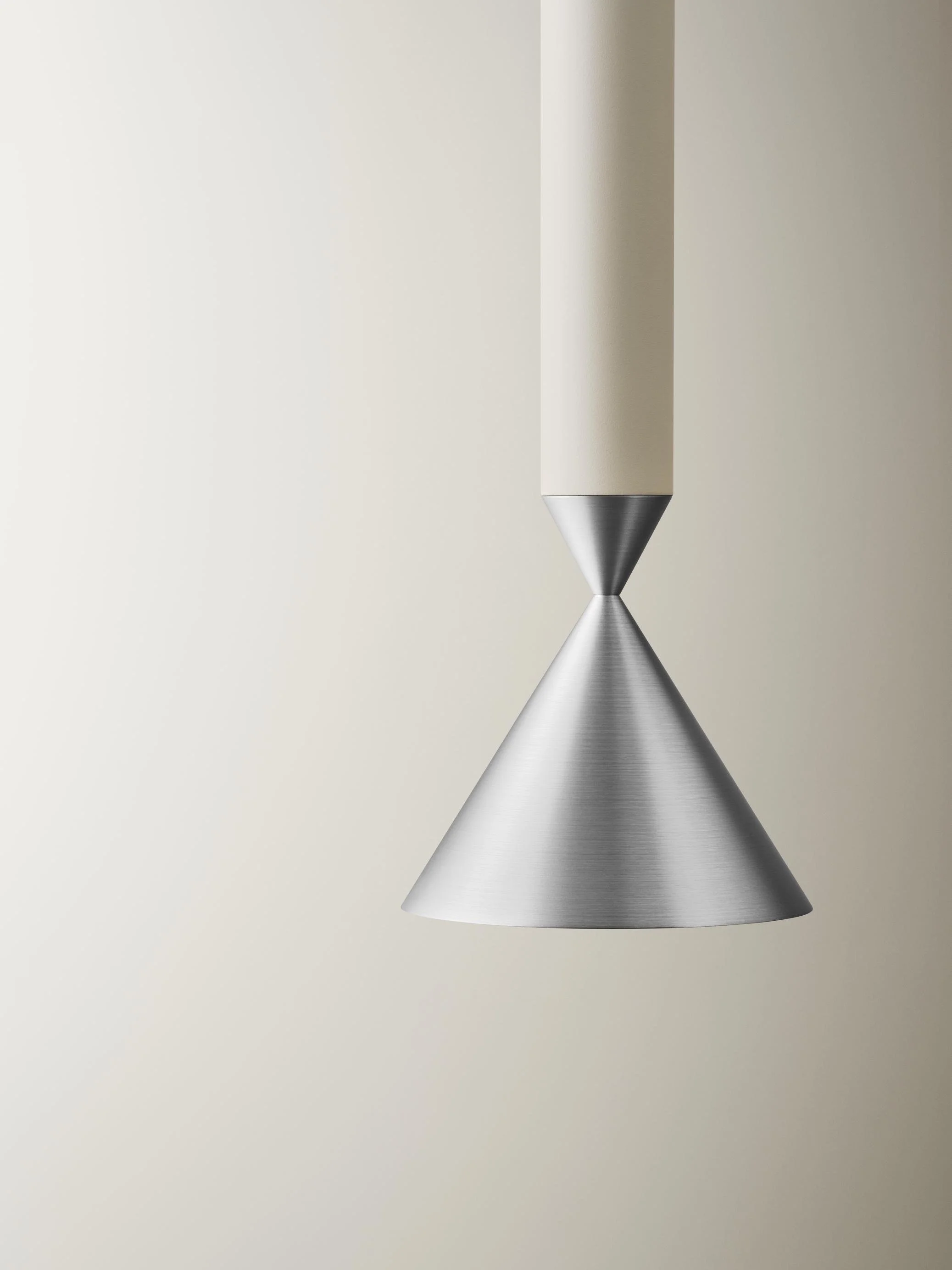 Close-up of a modern pendant light with a conical metal shade hanging from a ceiling.