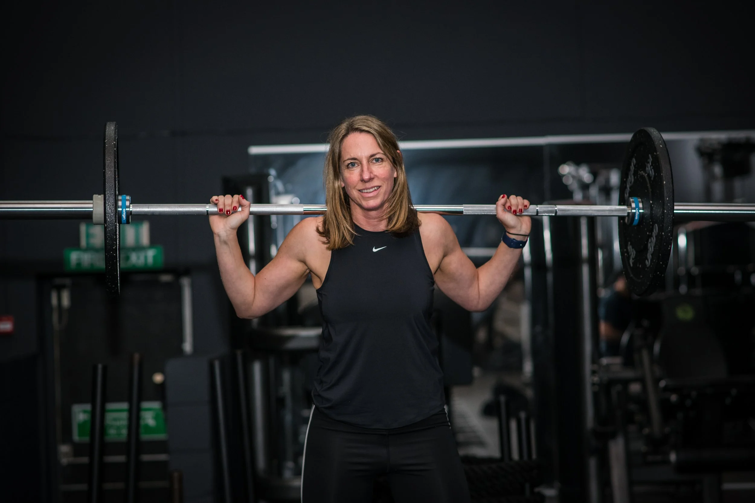 Woman lifting a barbell in a gym.
