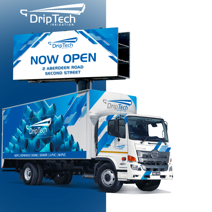 A white delivery truck with DripTech branding parked in front of a building, with a large billboard above it advertising the new location at Aberdeen Road and Second Street. The truck and billboard feature blue and white graphics.