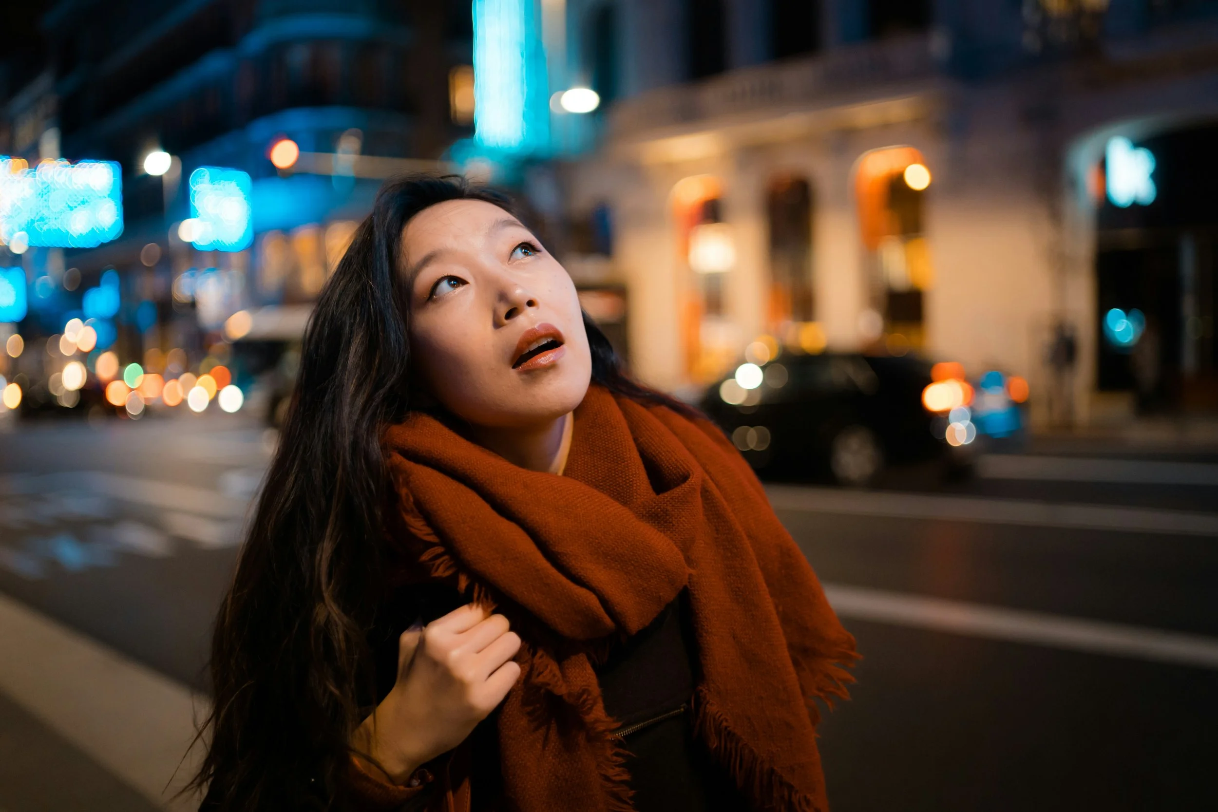 Woman in a city street looking upwards for inspiration