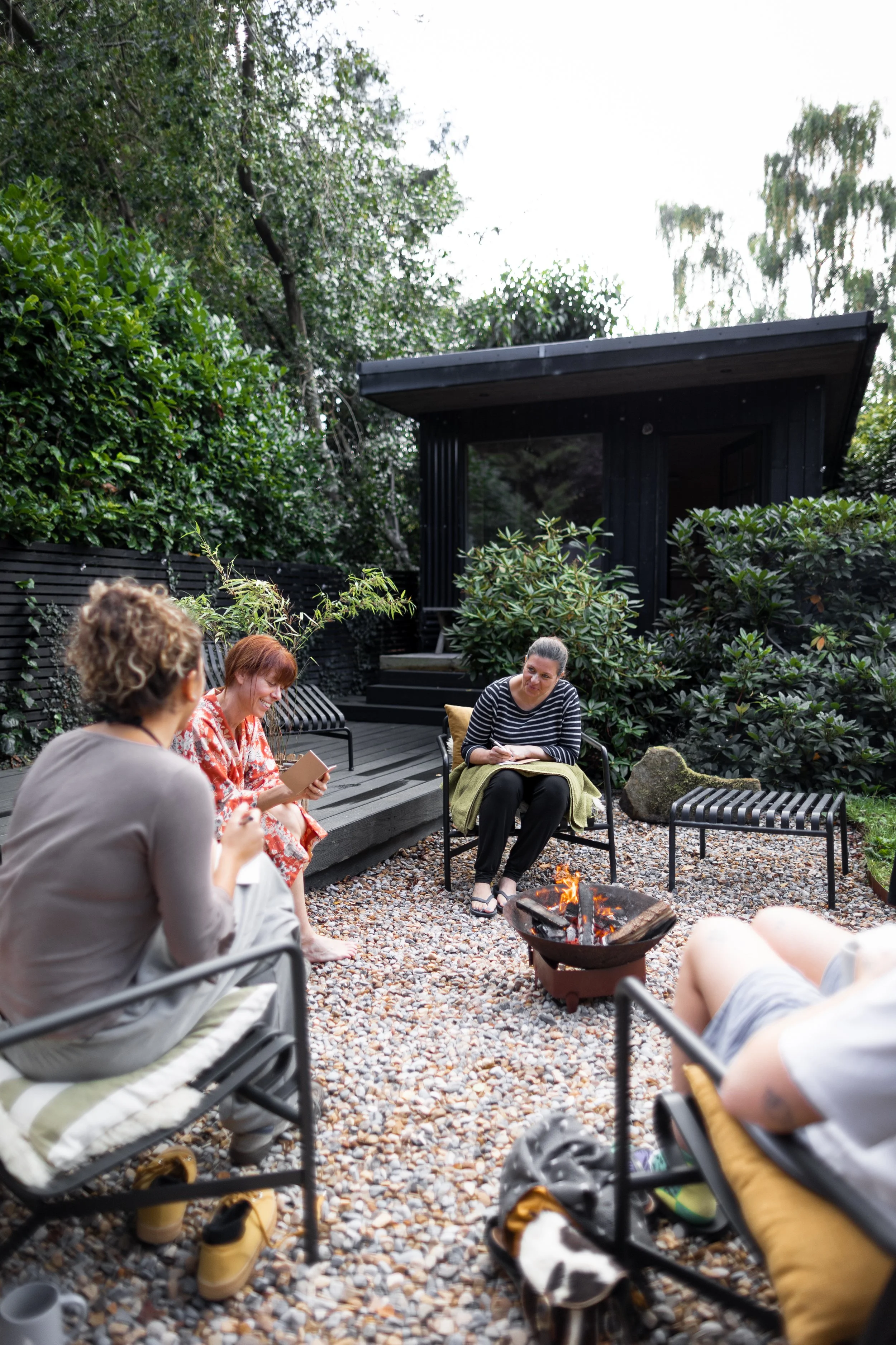 View of a group talking and journalling around the firepit