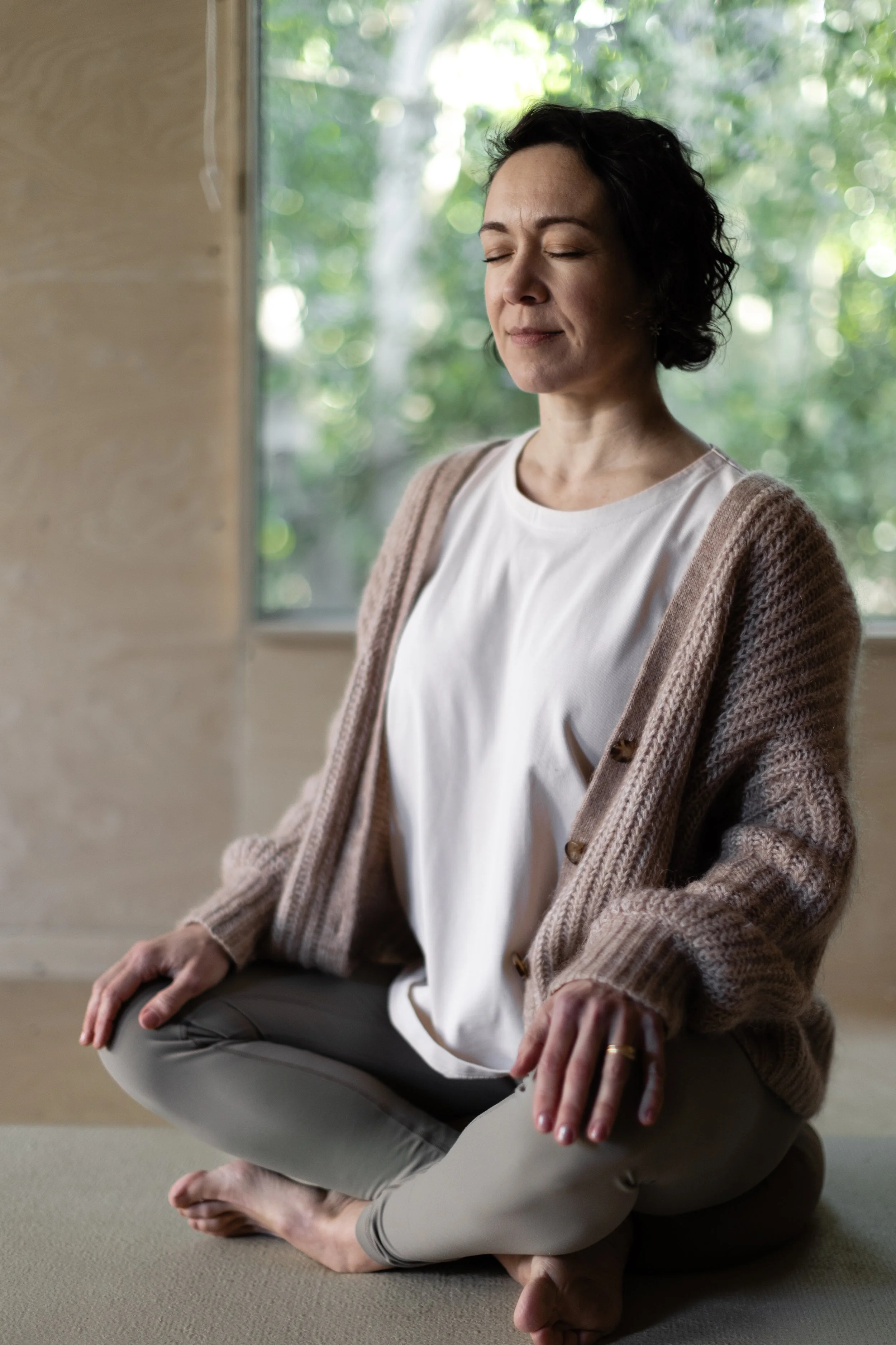 Founder Alice sat in meditation with the garden seen through the window