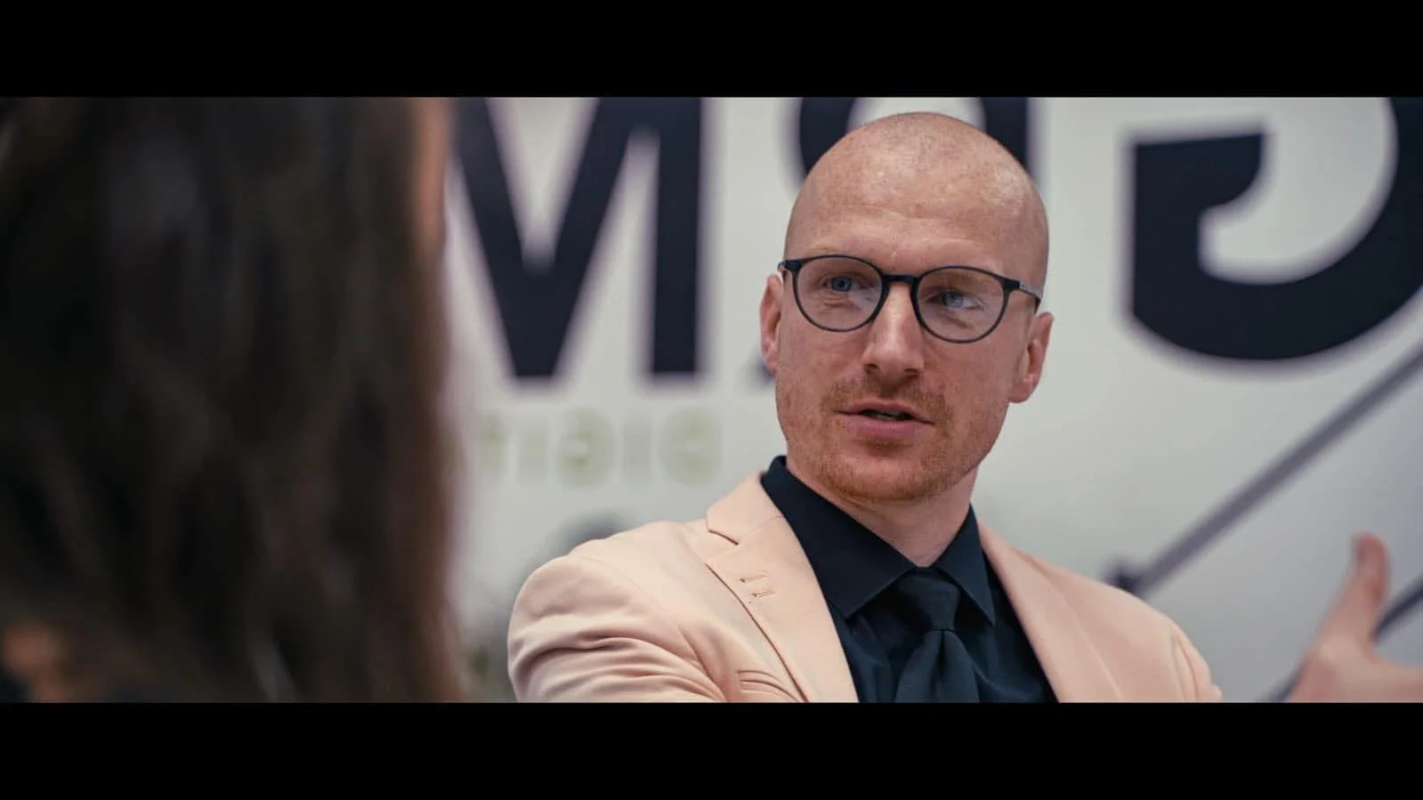 A man providing executive presentation coaching, engaged in conversation with a woman, in an office setting.