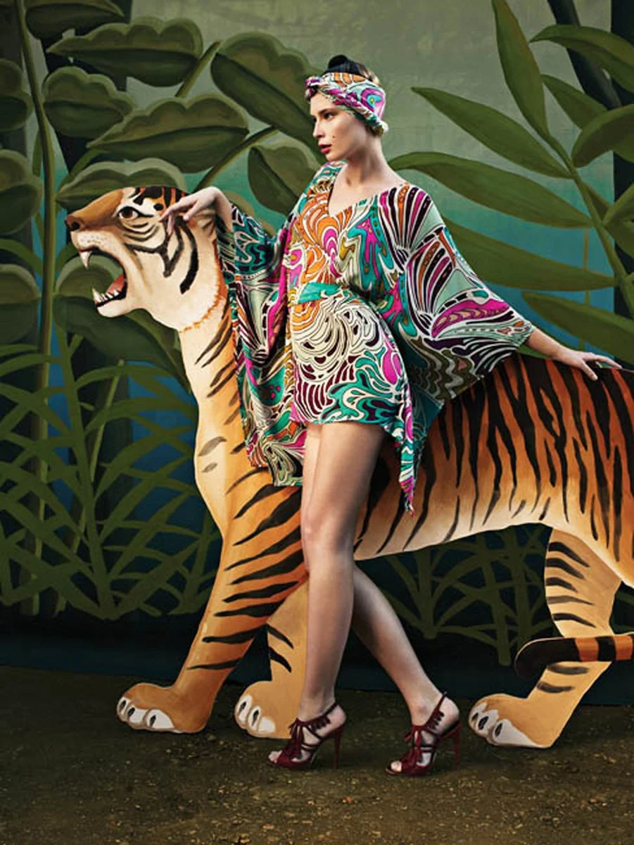 Vibrant patterns inspired by painter Henri Rousseau, jungle-themed. whimsical and bohemian aesthetic, with models posing against lush, theatrical backdrops featuring a painted cutout tiger