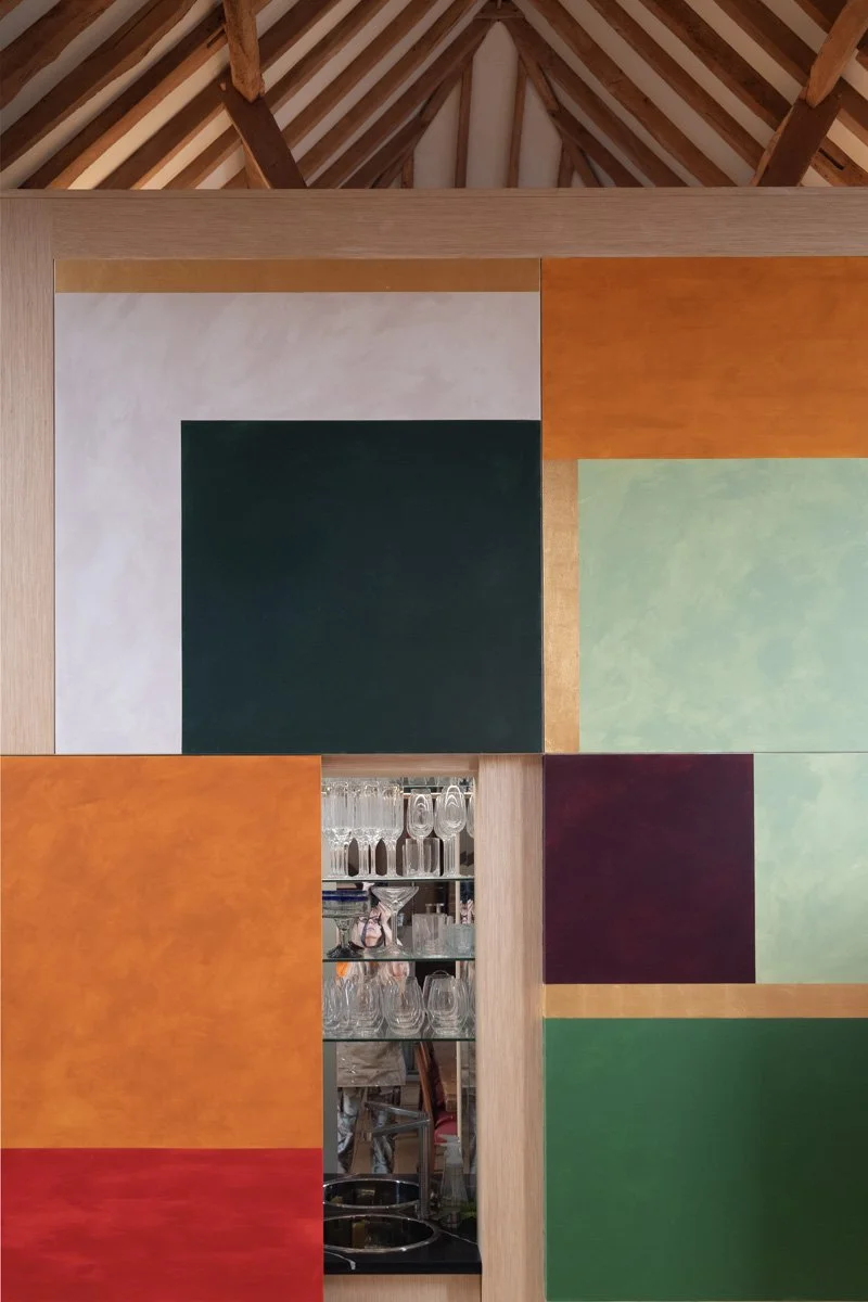 detail of a modern vibrant colour block mural on panels doors concealing a drinks cabinet