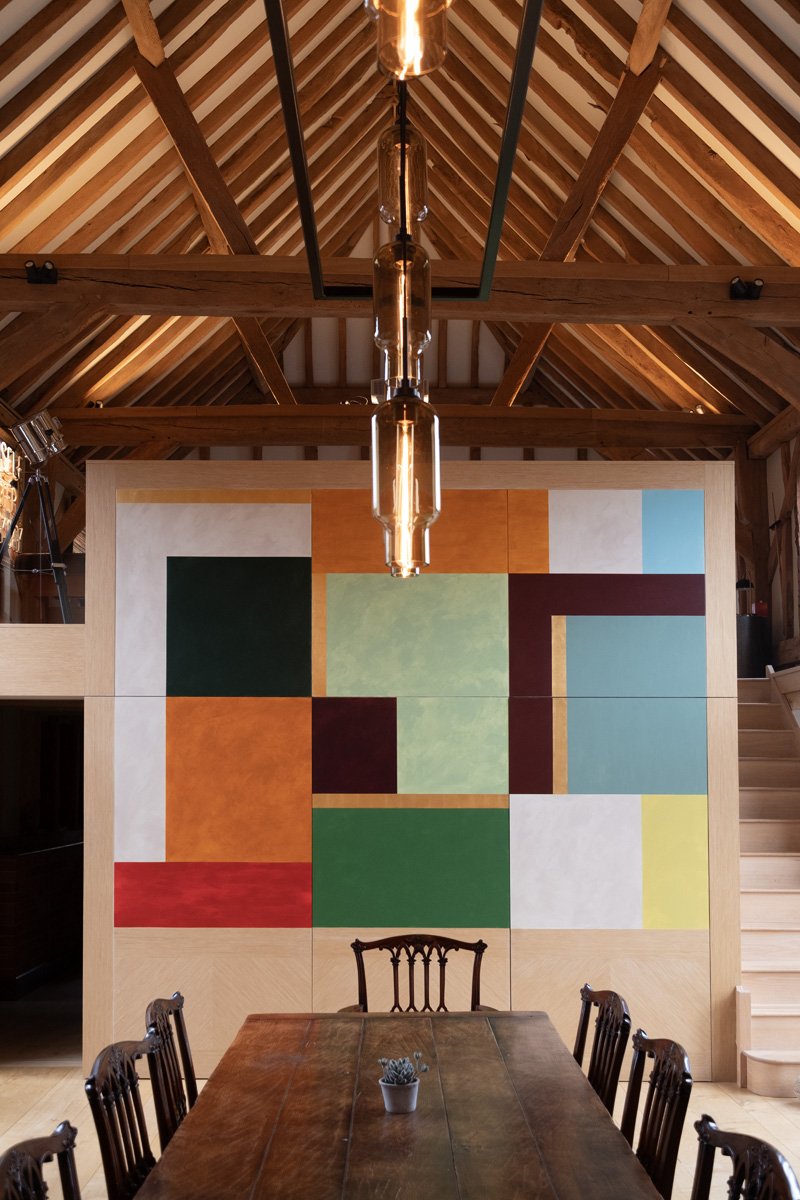 Interior of beamed barn modern conversion with vibrant colour block mural