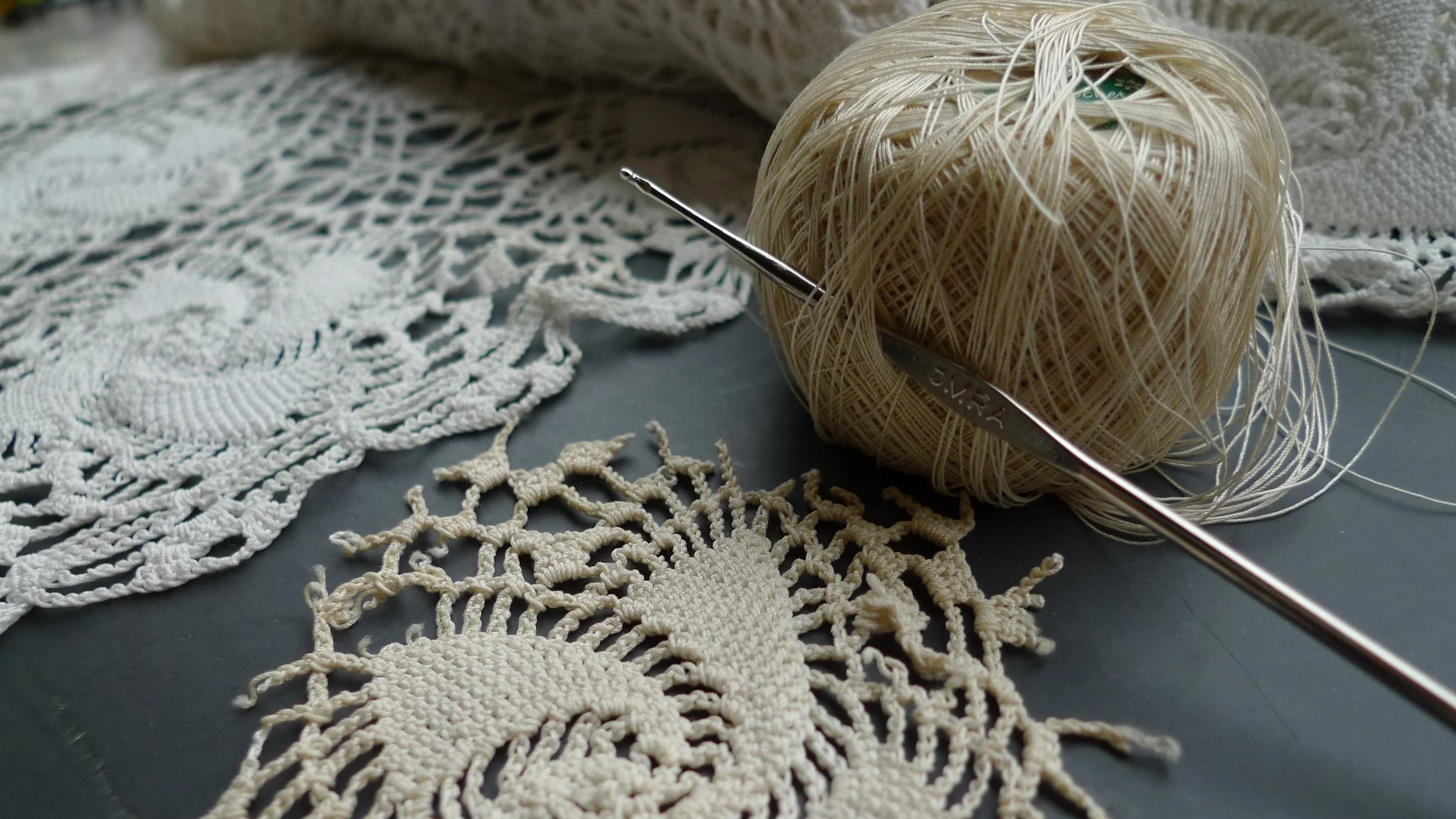 Various balls of yarn and knitting needles on a textured blue surface