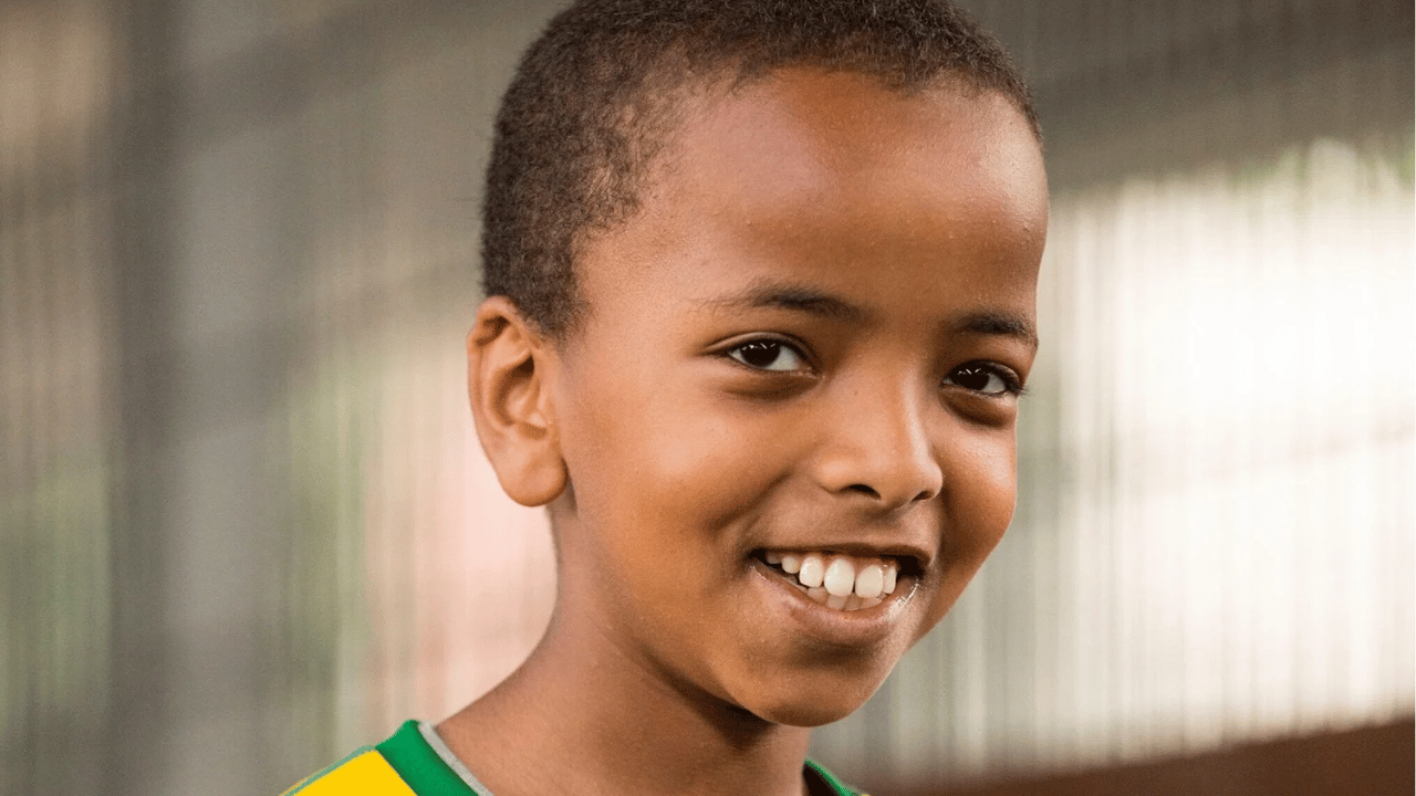 A young boy looks into the camera and smiles. He is a member of Solidarity Sports.