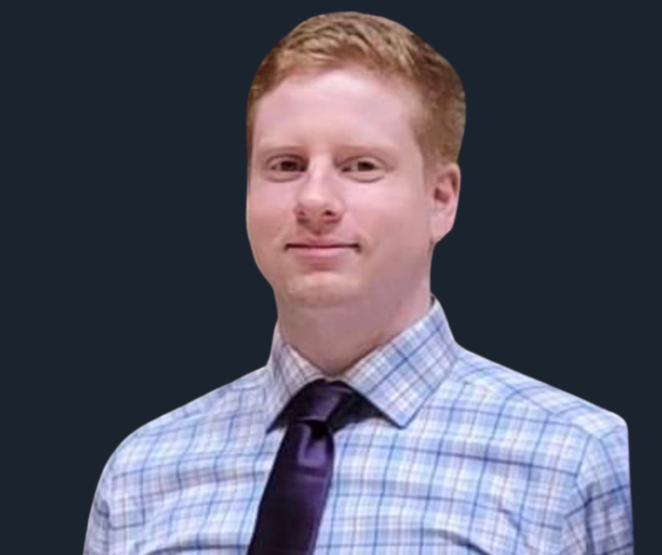 Portrait of a man with short red hair, wearing a blue checkered shirt and a dark tie.