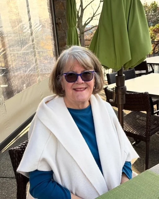 Kathleen DaRosa at a table wearing sunglasses and a white sweater.