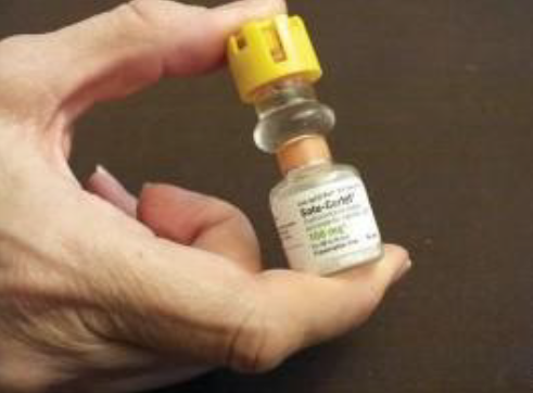 A hand holding a Solu-Cortef injection bottle.