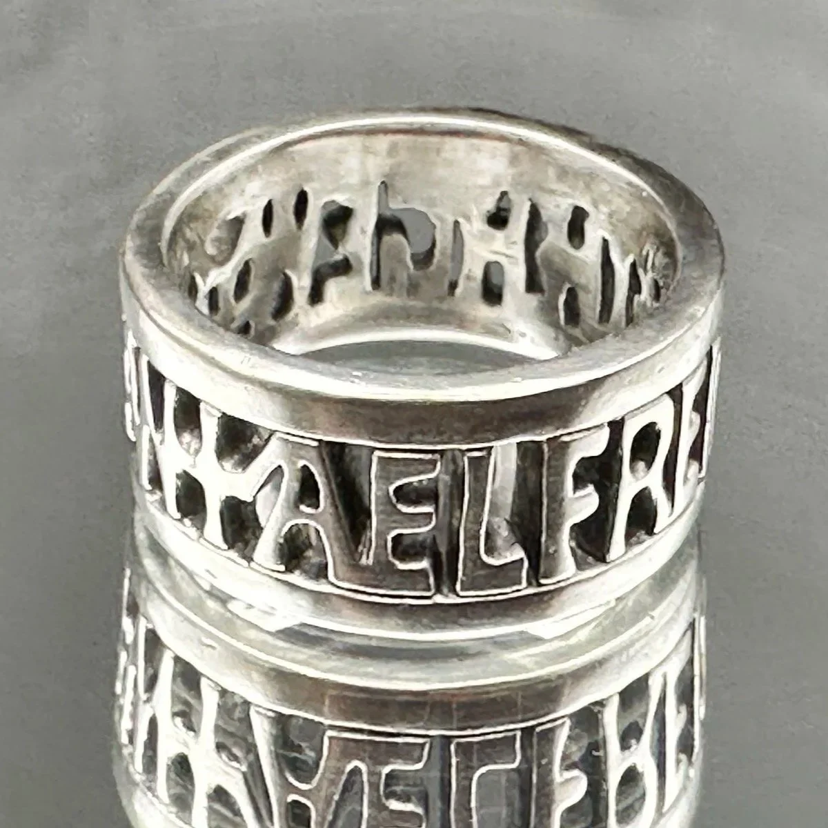 Close-up of The Alfred Ring, handmade in sterling silver, sitting on a mirror