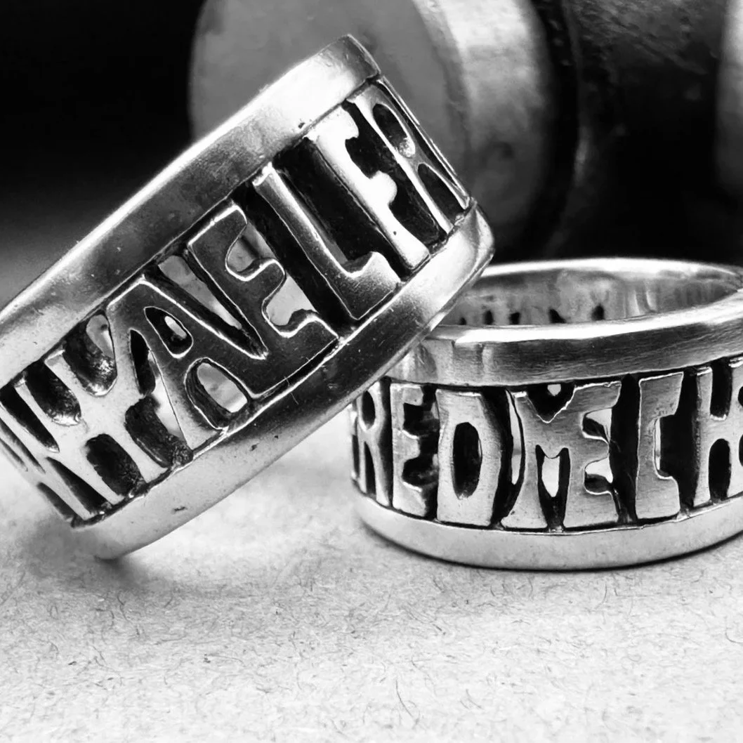 Two handmade Anglo-Saxon and Viking-age sterling silver rings with a Thor hammer in the background