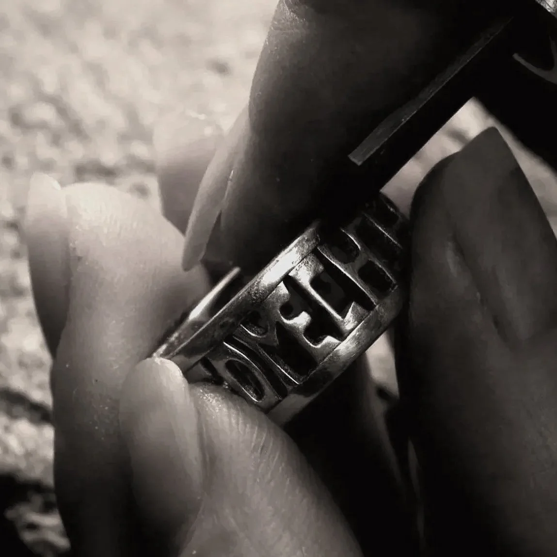 Close-up of the jeweller’s hand holding the sterling silver Alfred Ring along with an engraving tool